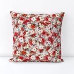 Decorative pillow featuring red and pink poinsettias with green leaves on a light background